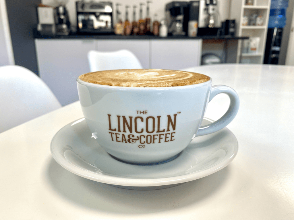 A cup of latte; cup text: The Lincoln Tea and Coffee Co.